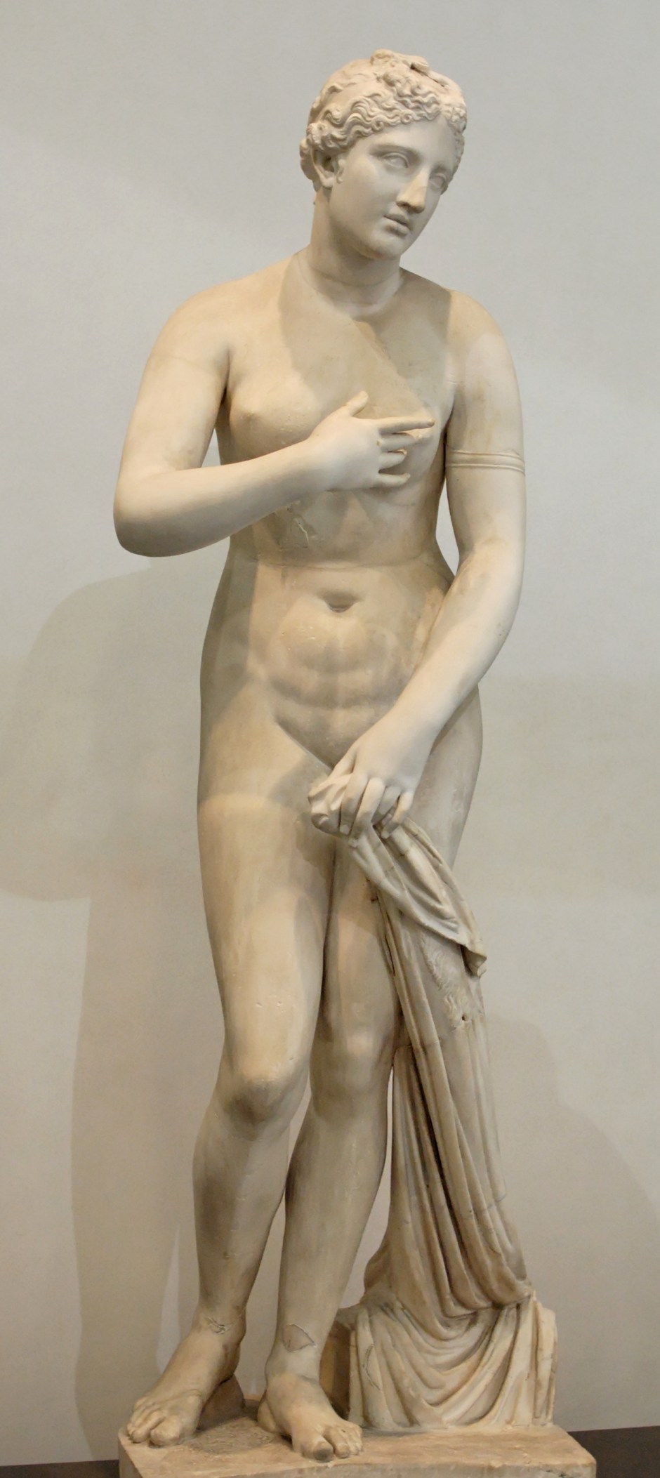The Aphrodite of Menophantos, dating from 1C BC is one of many variants of a sculptural pose called the Venus Pudica (modest Venus). It derives from a sculpture by Praxiteles but has been adjusted in two key ways. Firstly, Venus is adopting an aware and self-conscious pose and, secondly, the position of her arms has been adjusted to protect her modesty. That intrinsic modesty has made this one of the most enduring forms of female nude.
